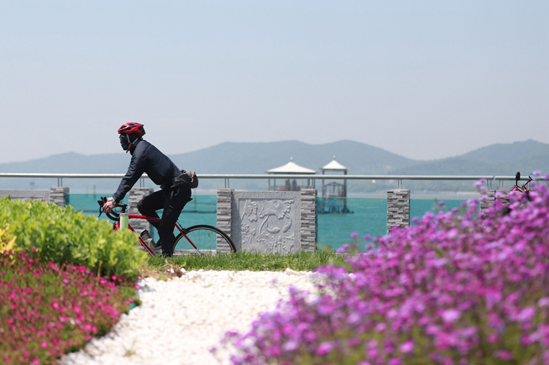 市民在風(fēng)景如畫(huà)的環(huán)湖路上騎行